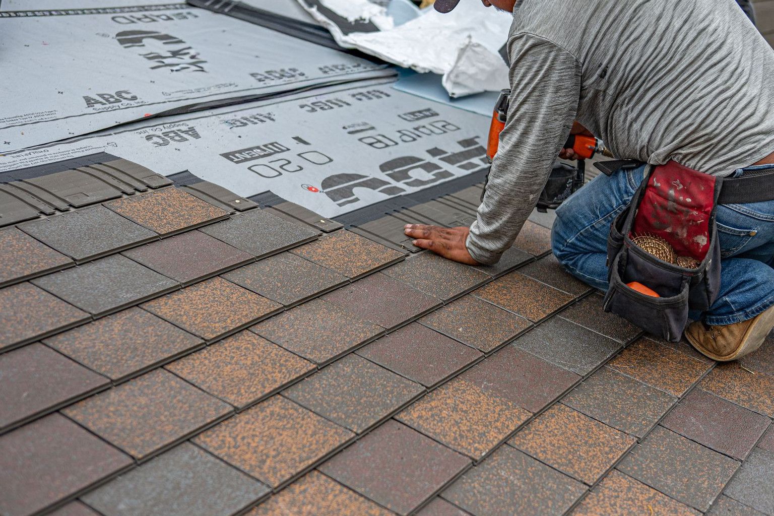 Skilled roofer installing asphalt shingles, ensuring quality home renovation.